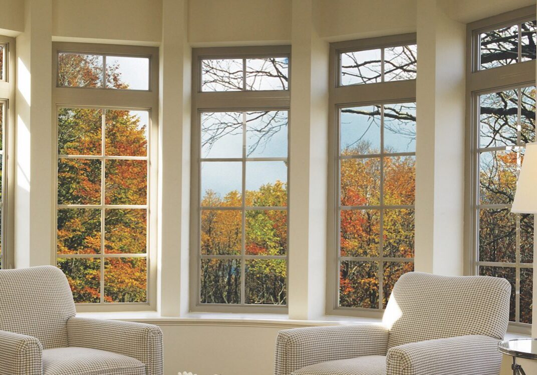 Two armchairs near bay windows with fall foliage